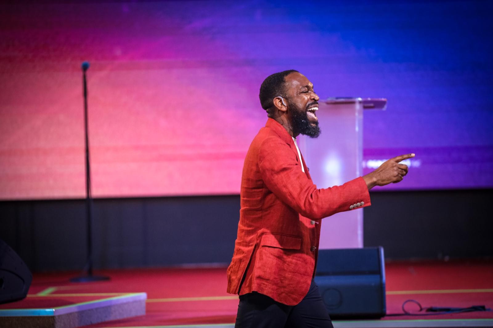 Rev'd Gerald Gyane preaching in red blazer